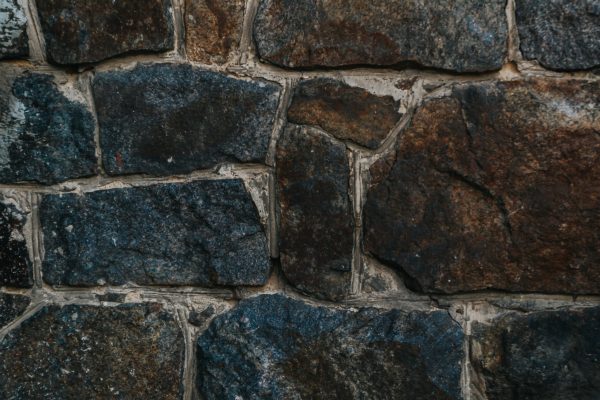 A wall made of stone with a blue and gray color. The wall is very rough and has a lot of texture