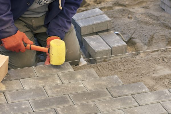 A closeup shot of a construction worker laying the paving slab with hammers